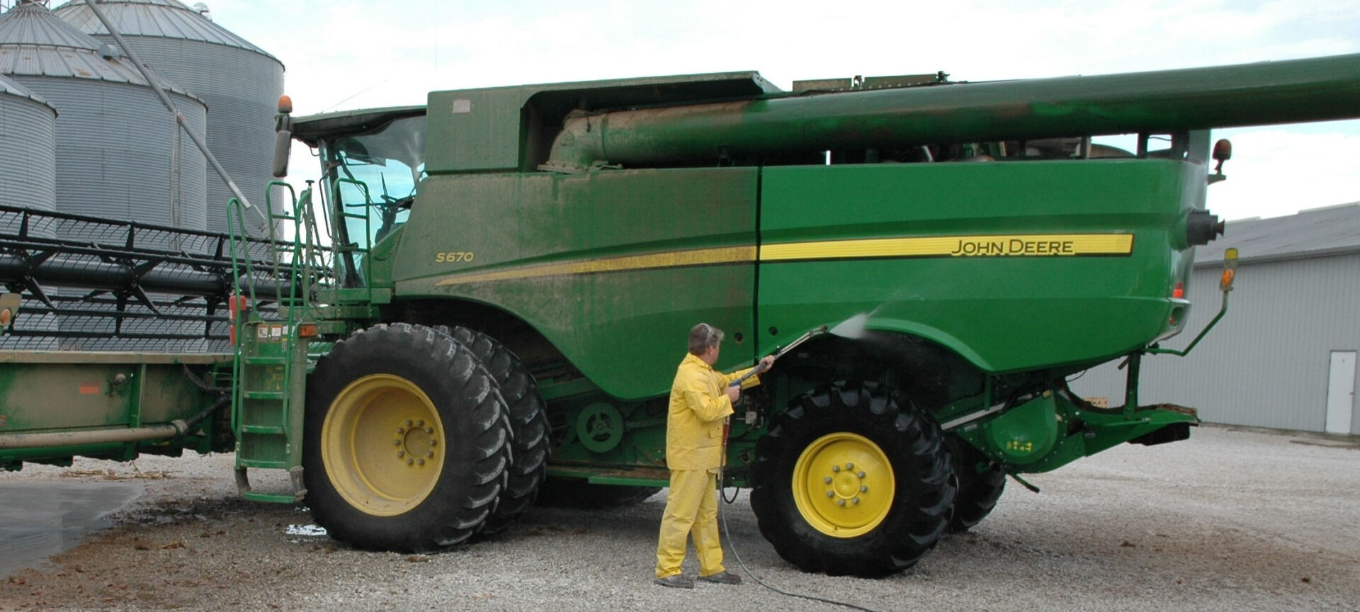 A person using a power washer to clean a large vehicle